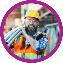 Construction worker carrying pipes